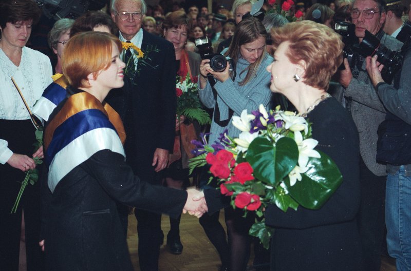 LU 81. gadskārtai veltītā Senāta svinīgā sēde. Latvijas Valsts prezidenti Vairu Vīķi-Freibergu pēc LU Goda doktores diploma saņemšanas sveic studenšu korporācijas 'Spīdola' pārstāves.