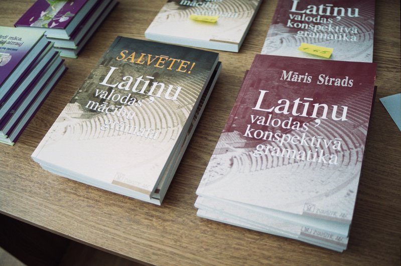 Grāmatu 'Salvēte! Latīņu valodas mācību grāmata' un 'Latīņu valodas konspektīvā gramatika' (Autors - Māris Strads). Grāmatu vāki.