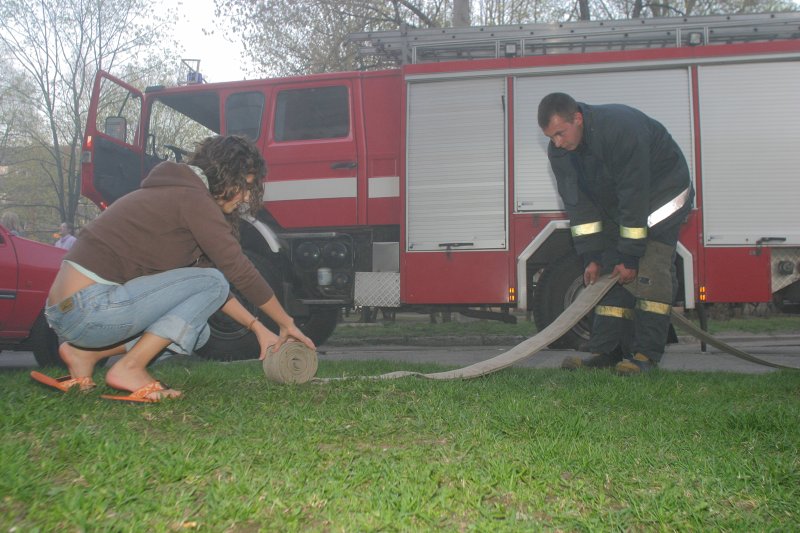 Ugunsdzēsības mācības LU dienesta viesnīcā Buļļu ielā 5. Studente palīdz ugunsdzēsējam saritināt šļūteni.