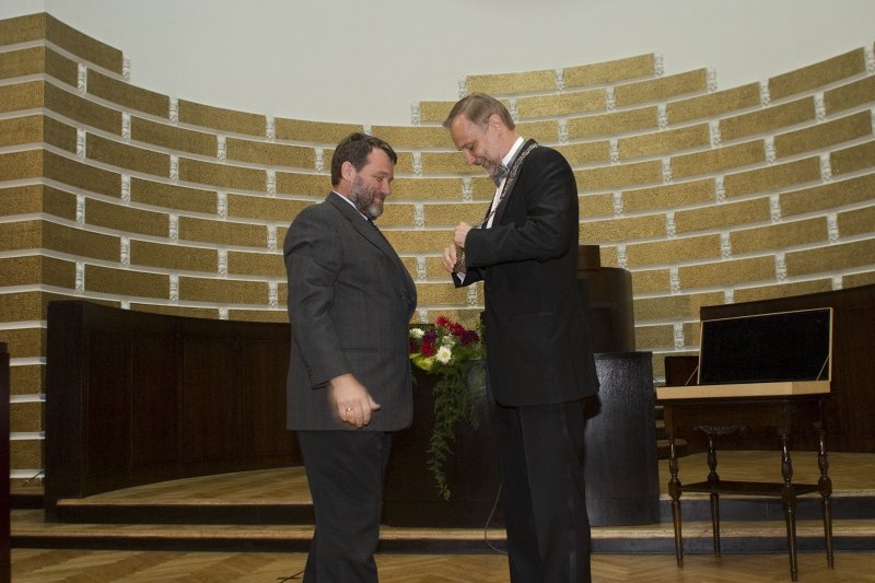 LU darbinieku ikgadējā sanāksme. No kreisās: LU Senāta priekšsēdētājs Juris Rozenvalds uzliek rektora amata ķēdi rektoram Mārcim Auziņam.