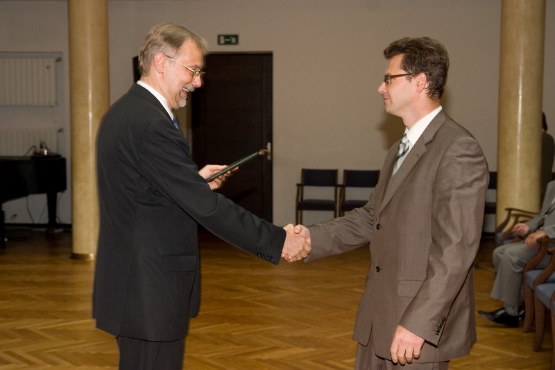 LU darbinieku sapulce. LU rektors Mārcis Auziņš (pa kreisi) pasniedz asociētā profesora diplomu Edgaram Sūnam.