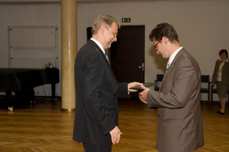 LU darbinieku sapulce. LU rektors Mārcis Auziņš (pa kreisi) pasniedz asociētā profesora diplomu Edgaram Sūnam.