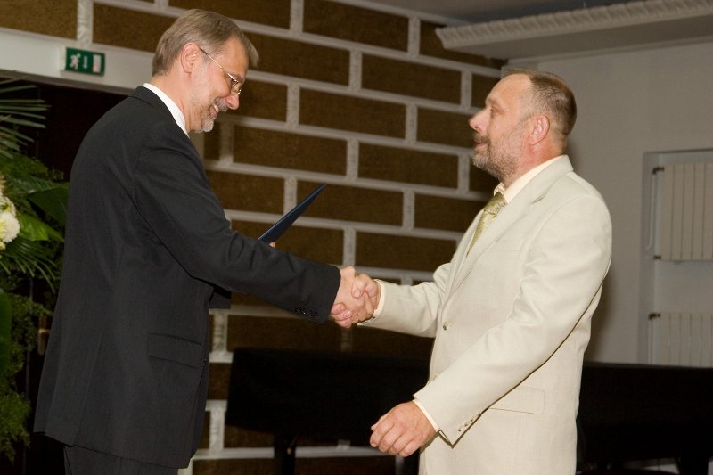 LU darbinieku sapulce. LU rektors Mārcis Auziņš (pa kreisi) pasniedz pateicības rakstu prof. Jānim Švirkstam.