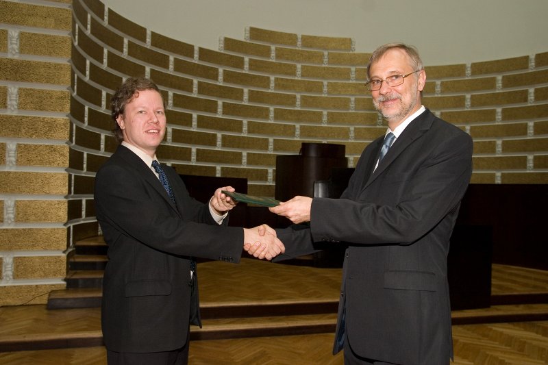 LU darbinieku sapulce. LU rektors Mārcis Auziņš (pa labi) pasniedz profesora diplomu Andrim Ambainim.