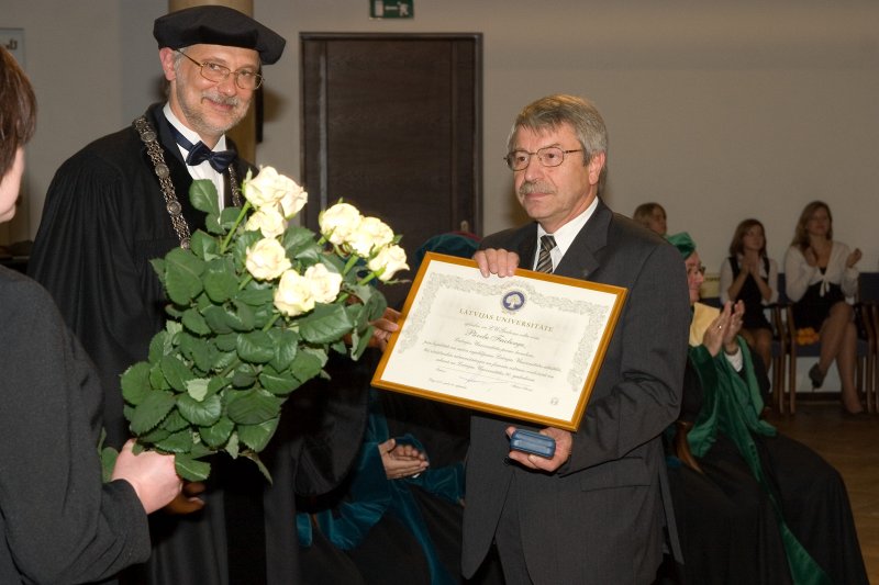 Latvijas Universitātes 90. gadadienai veltīta svinīgā LU Senāta sēde. LU rektors Mārcis Auziņš (pa kreisi) pasniedz LU Ģerboņa Zelta zīmi bijušajam LU kancleram Pāvelam Fricbergam.
