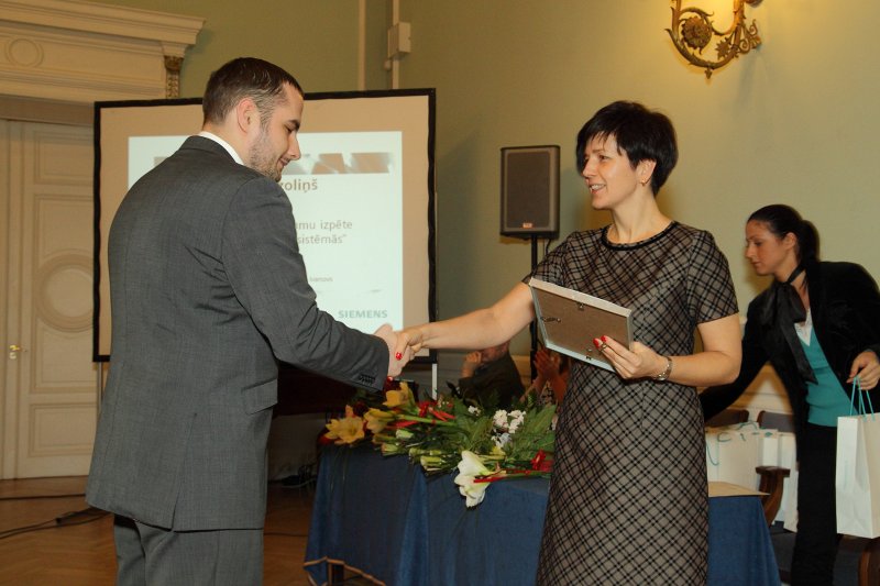 Vernera fon Sīmensa Izcilības balvu (Werner von Siemens Excellence Award) pasniegšanas ceremonija. Siemens Latvijas filiāles vadītāja Maija Baumane sveic balvas saņēmēju RTU maģistru Oskaru Ozoliņu.