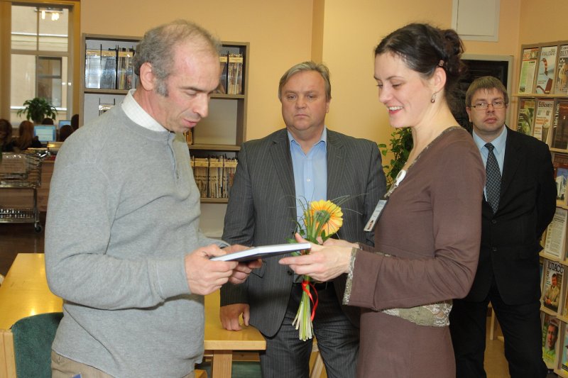 Profesora Mihaila Hazana 60 gadu jubilejai veltītās izstādes 'LU Ekonomikas un vadības fakultātes prof. Mihaila Hazana zinātniskā darbība un intelektuālie sasniegumi' atklāšana LU Bibliotēkas Ekonomikas zinātņu bibliotēkā. LU Bibliotēkas bibliotekāre Edīte Mališeva pasniedz dāvanu prof. Mihailam Hazanam.