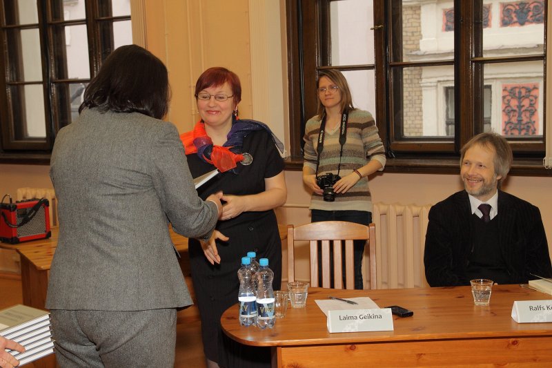 Apaļā galda saruna 'Latviešu mācītāji - literāti'. LU Bibliotēkas direktore Iveta Gudakovska diskusijas dalībniekiem dāvina grāmatu par bibliotēku.