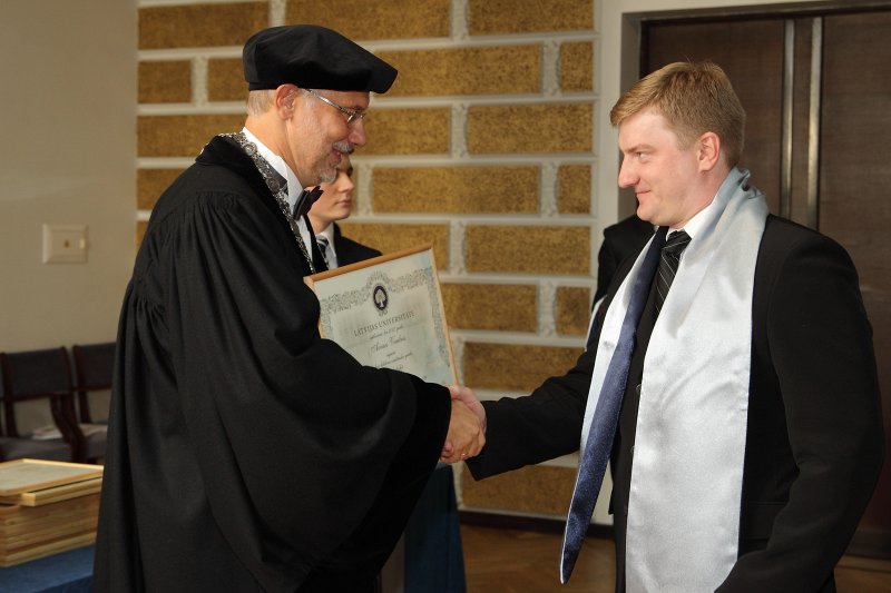 Latvijas Universitātes 94. gadadienai veltīta LU Senāta svinīgā sēde. LU doktoru promocijas ceremonija. LU rektors prof. Mārcis Auziņš pasniedz LU Apliecinājuma rakstu dr.  Aivaram Vembrim.