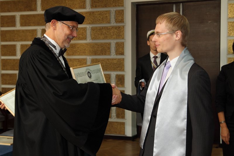 Latvijas Universitātes 94. gadadienai veltīta LU Senāta svinīgā sēde. LU doktoru promocijas ceremonija. LU rektors prof. Mārcis Auziņš pasniedz LU Apliecinājuma rakstu dr. Jānim Buholcam.