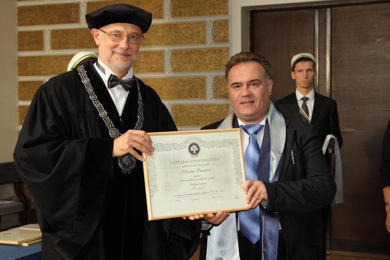 Latvijas Universitātes 94. gadadienai veltīta LU Senāta svinīgā sēde. LU doktoru promocijas ceremonija. LU rektors prof. Mārcis Auziņš pasniedz LU Apliecinājuma rakstu dr. Aināram Bambalam.