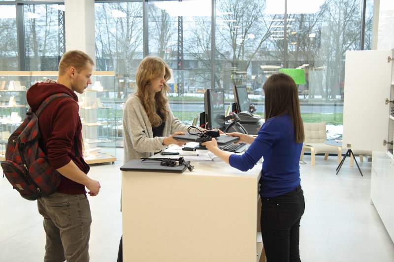 Latvijas Universitātes Dabaszinātņu akadēmiskais centrs. LU Bibliotēkas darbinece studentiem izsniedz datorus.