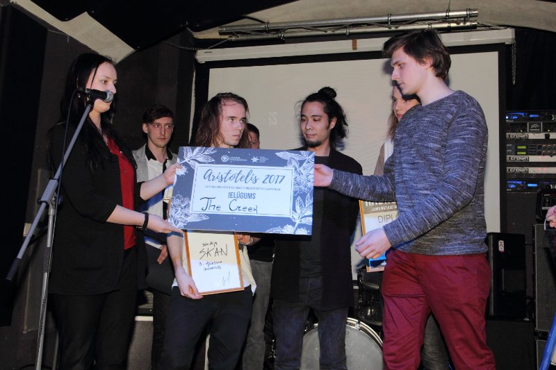 Jauno mūzikas grupu konkursa «Hadrons 2017» fināls klubā NABAKLAB. LU Studentu padomes priekšsēdētāja Signe Skutele konkursa 1. vietas ieguvējiem grupai 'The Creek' pasniedz ielūgumu piedalīties jauno studentu svētkos Aristotelis 2017.