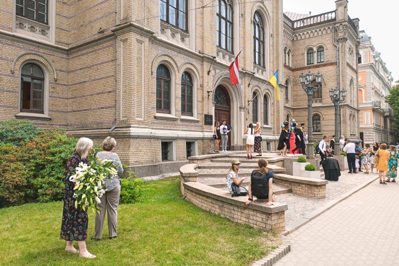 Absolventi un viesi pēc izlaiduma pie Latvijas Universitātes galvenās ēkas. null