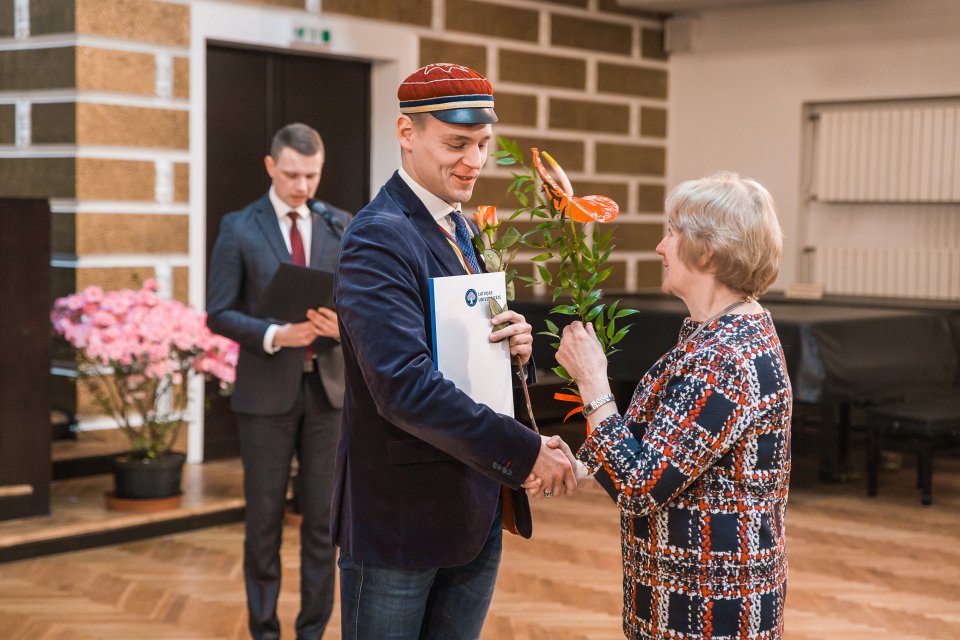 Latvijas Universitātes darbinieku kopsapulce. LU Muzeja krājuma glabātāju Rūdolfu Rubeni sveic prof. emeritus Aīda Krūze.